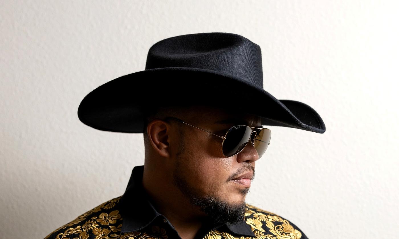 Glenn Awong, front man for Maoli, in a black cowboy hat against a white wall