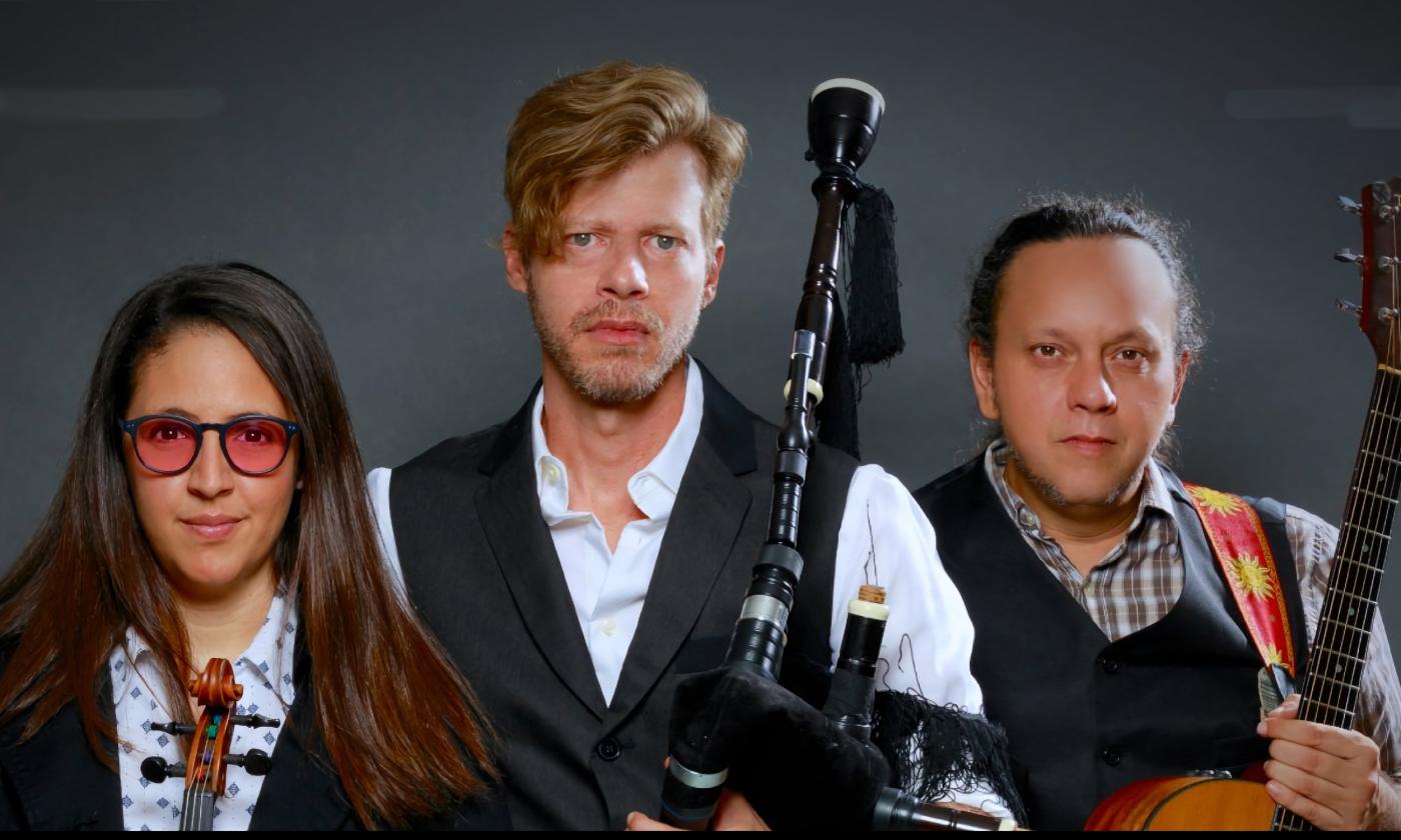 The three members of the band Gaêlica, standing in front of a grey wall