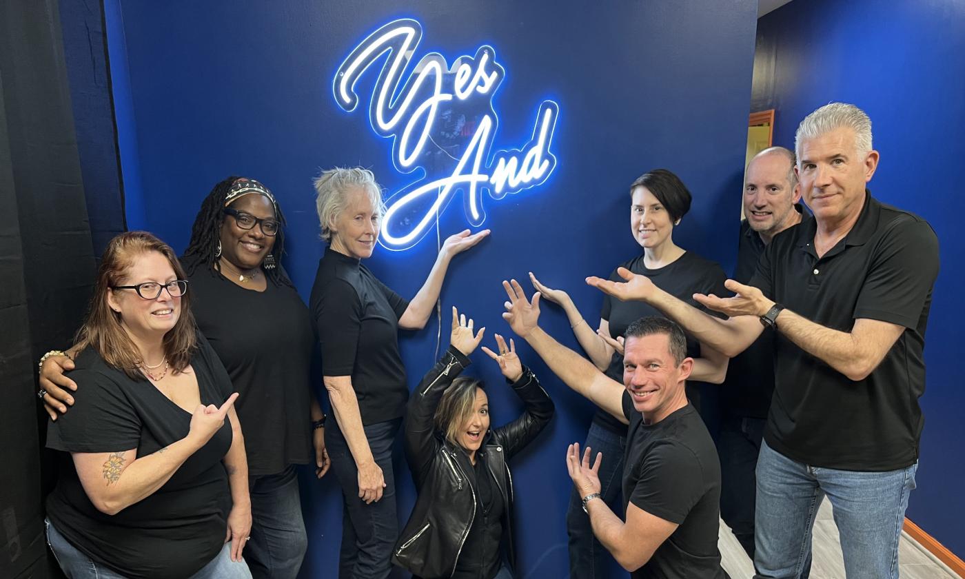 Students in black showcase clothes pose under the yes and sign