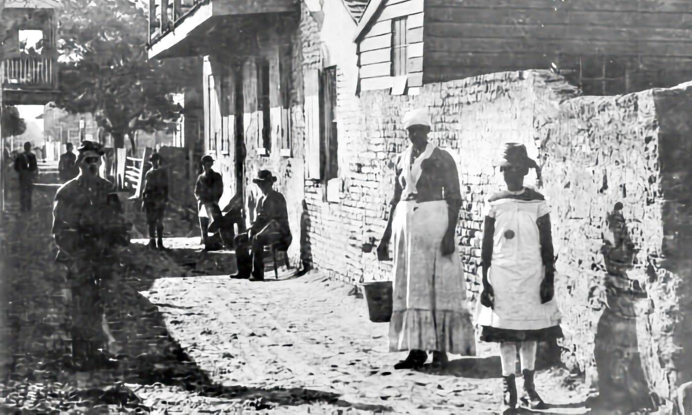 A B&W view down Charlotte St. Two Black women stand in the foreground on the right, with several others walking in the background.