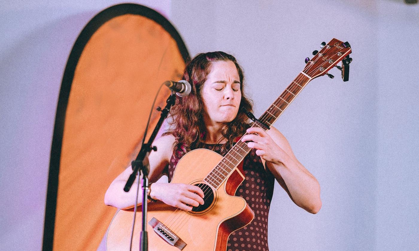 Songwriter Shawna Capsi performing onstage with her guitar