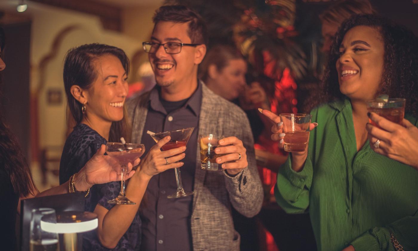 Audience members prior to the Magic Hideaway show, smiling and holding signature cocktails