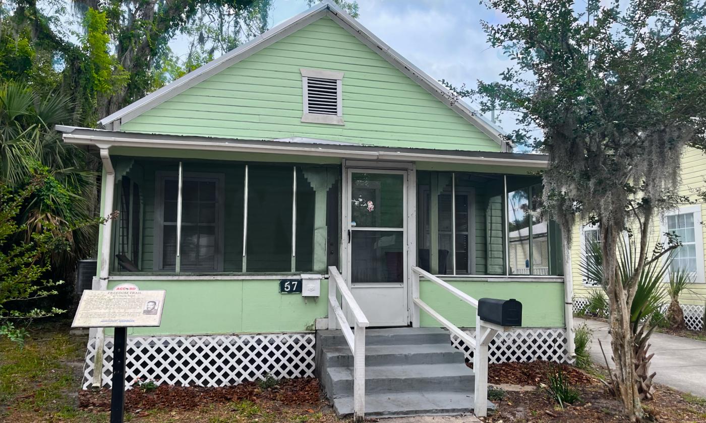 North-facing side of 57 Chapin St., a light green house with a screened-in porch and ACCORD Freedom Trail plaque out front.