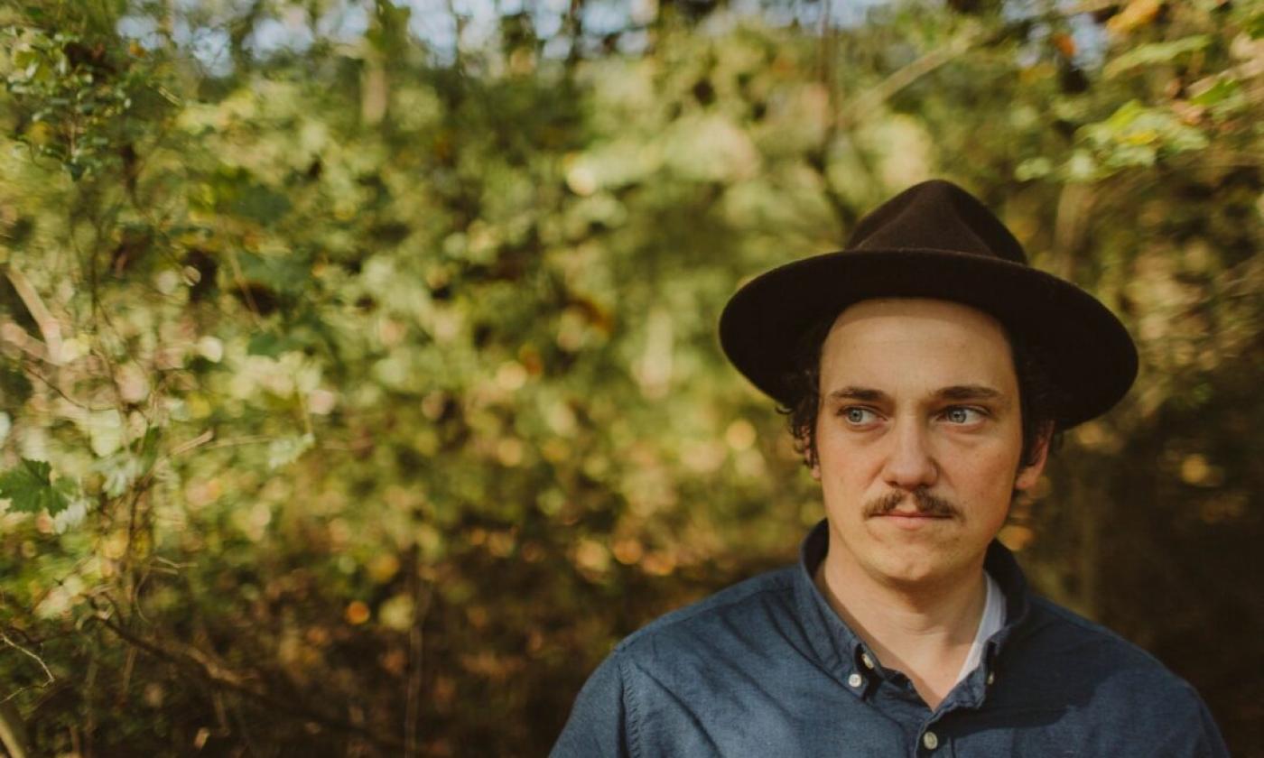 Jonathan Peyton poses in front of a large bush. 