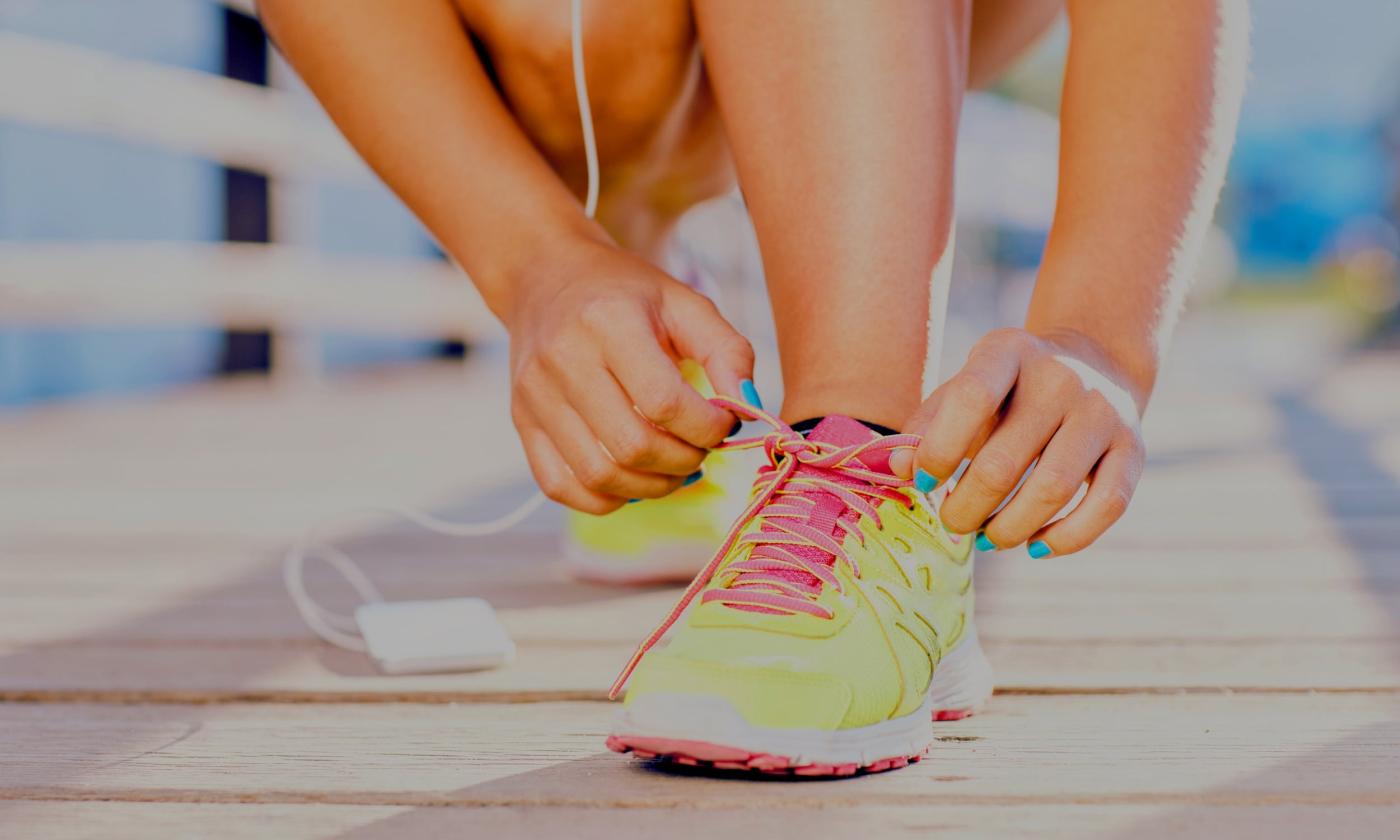 Runner tying shoes on the boardwalk while listening to music