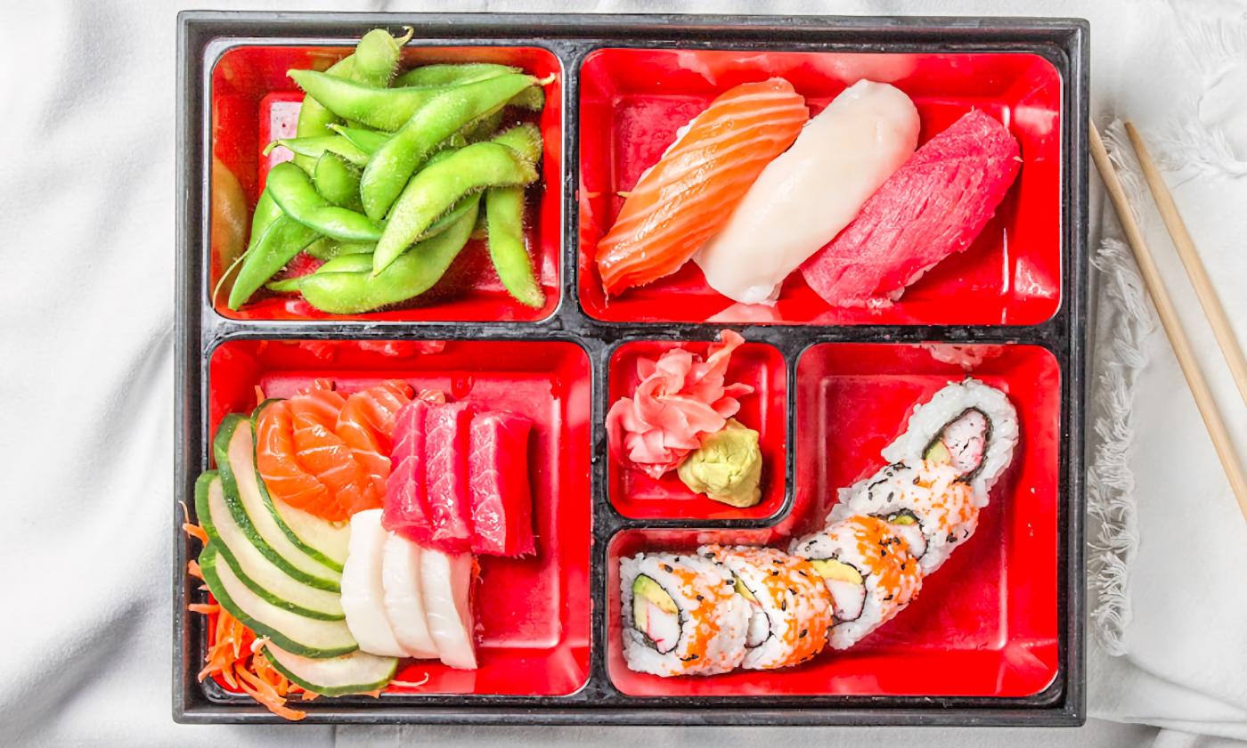 A sushi platter presented with assorted fish and edamame