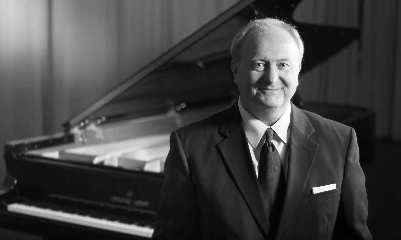 Pianist Dr. Stott Watkins standing in front of a grand piano