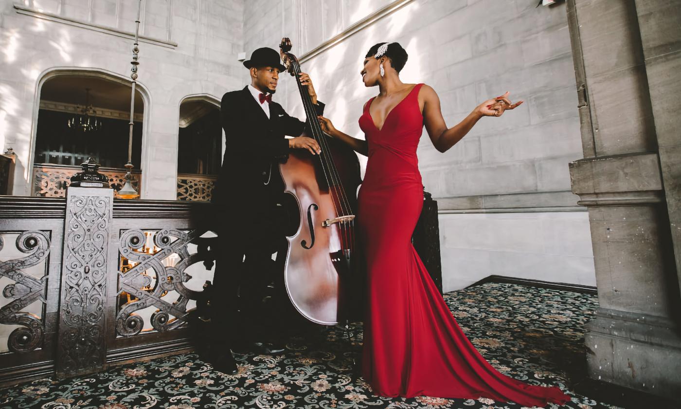 A vocalist in a red dress, singing with a well-dressed man playing an upright bass