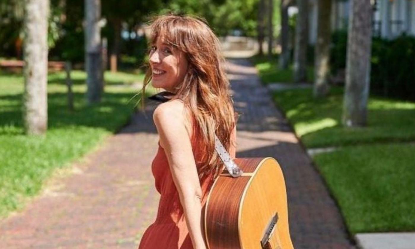 Alana DeBow walking with her guitar