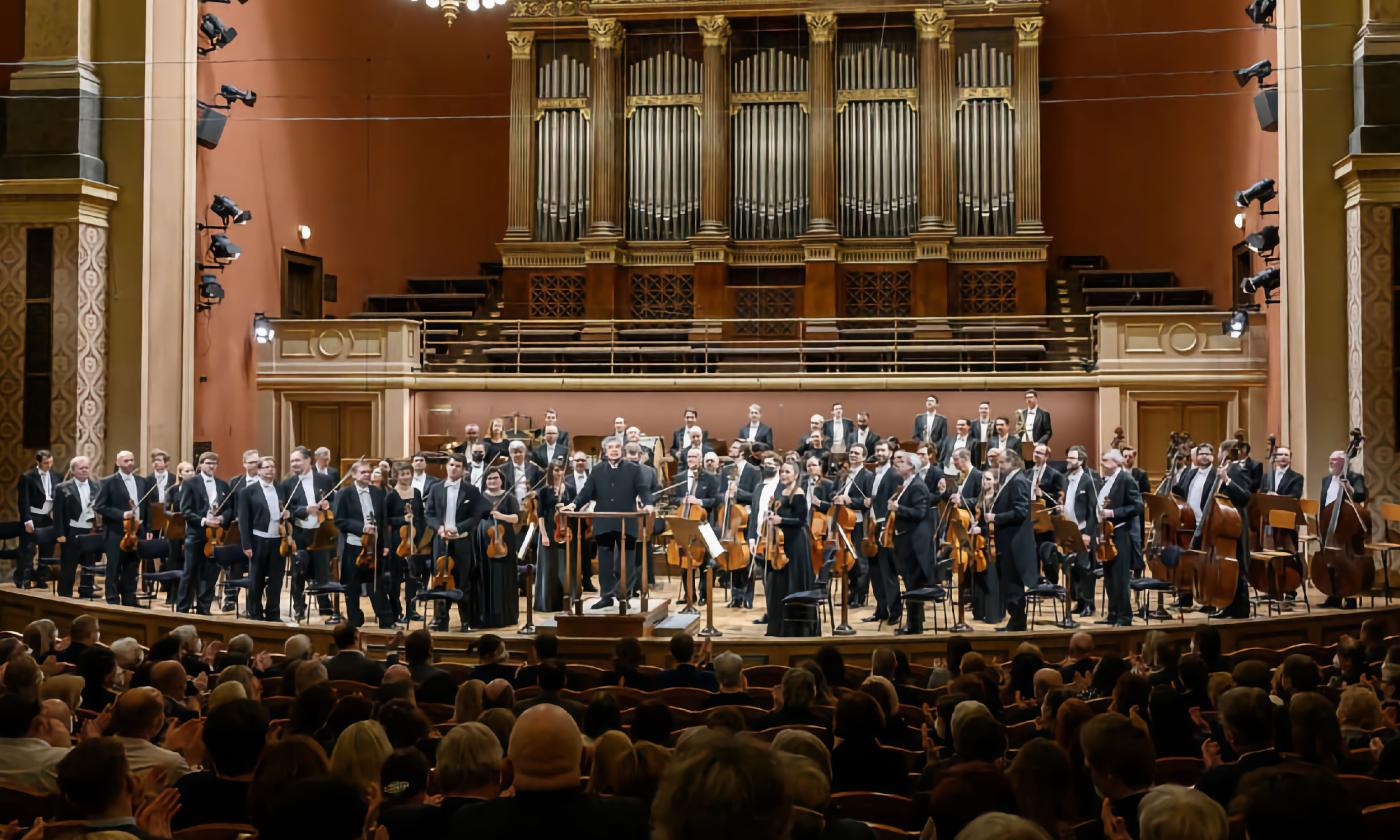 The Czech Philoharmonic Orchestra standing on stage to an audience ovation