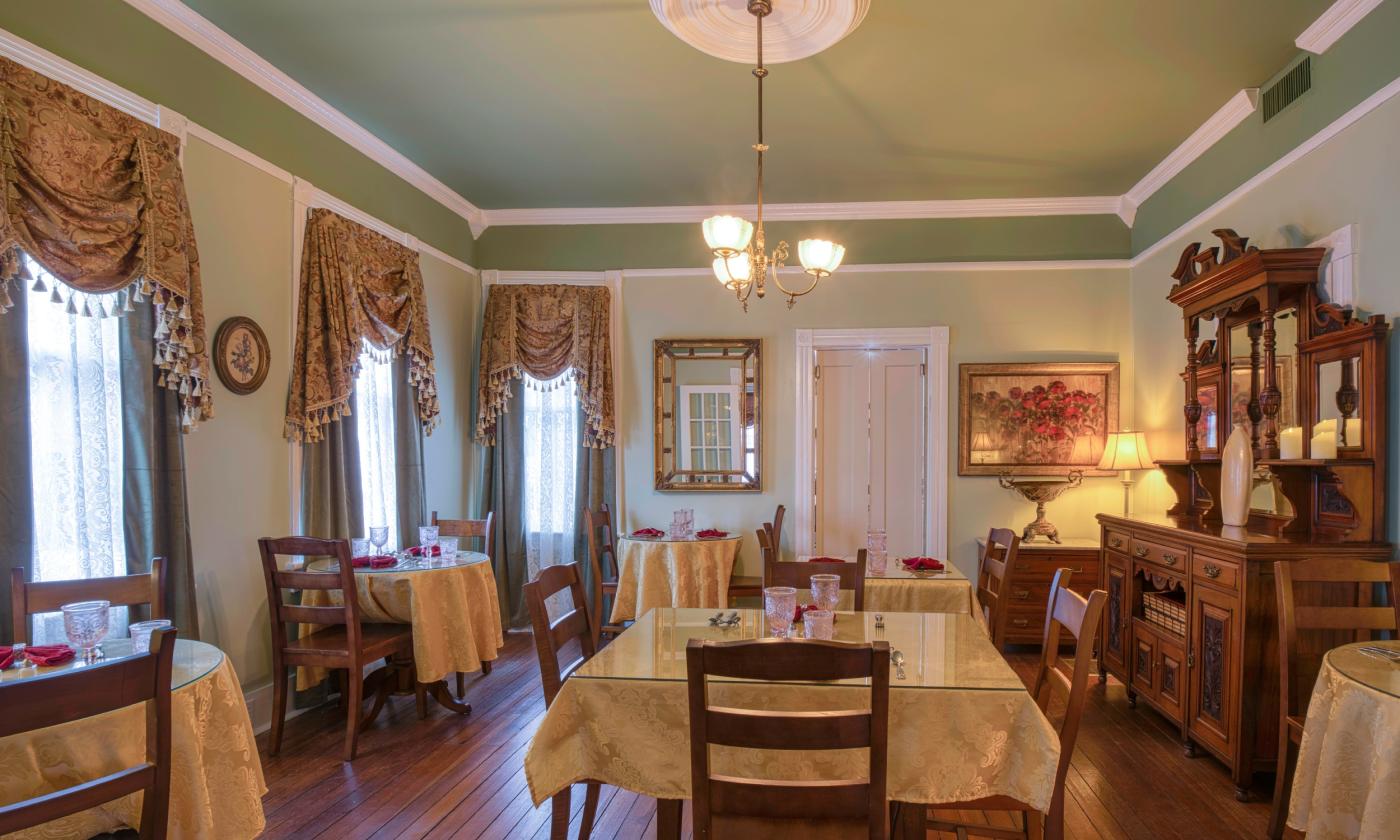 The large breakfast room at the bed and breakfast has gold damask tablecloths and a regal setting