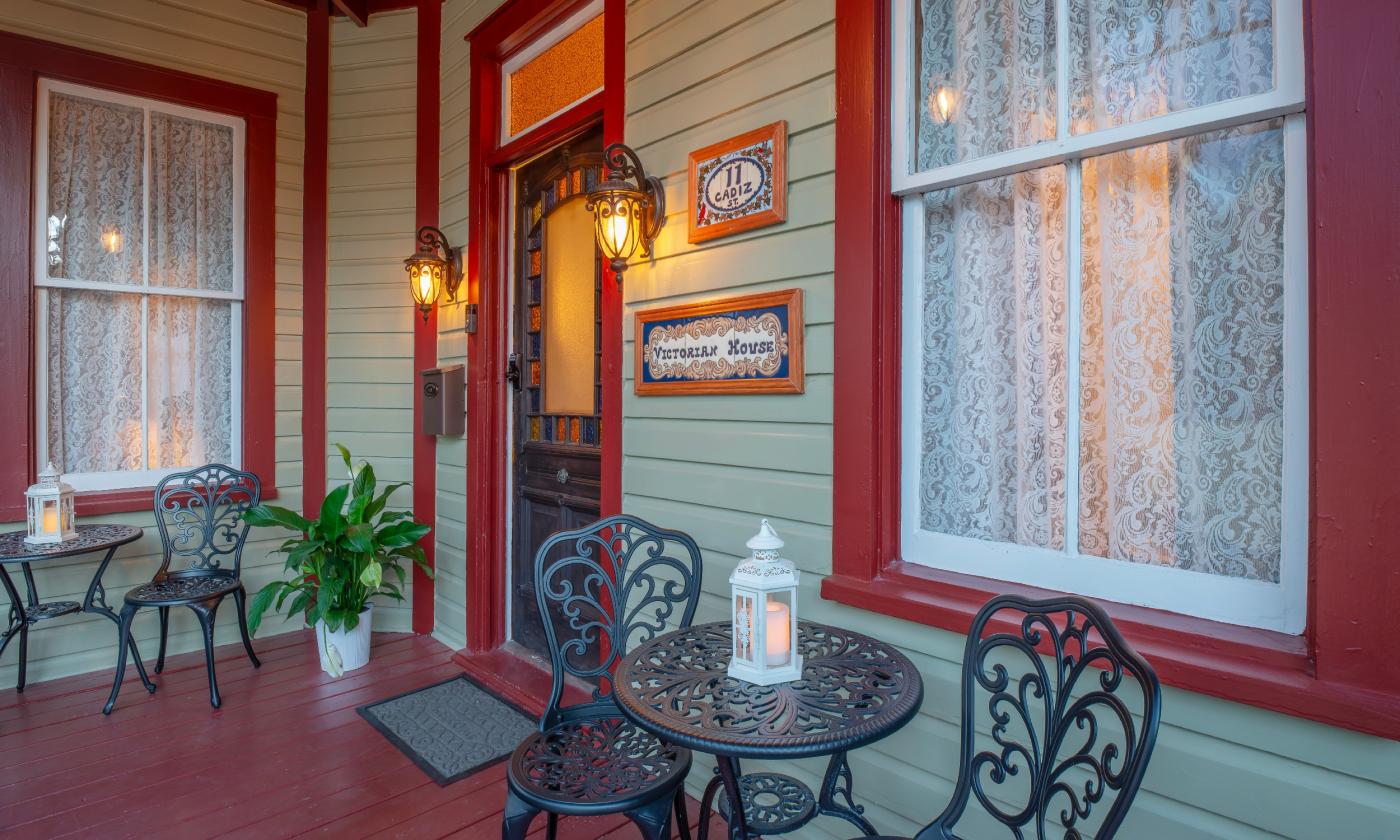 The entrance at a bed and breakfast property has wrought iron furniture on the porch