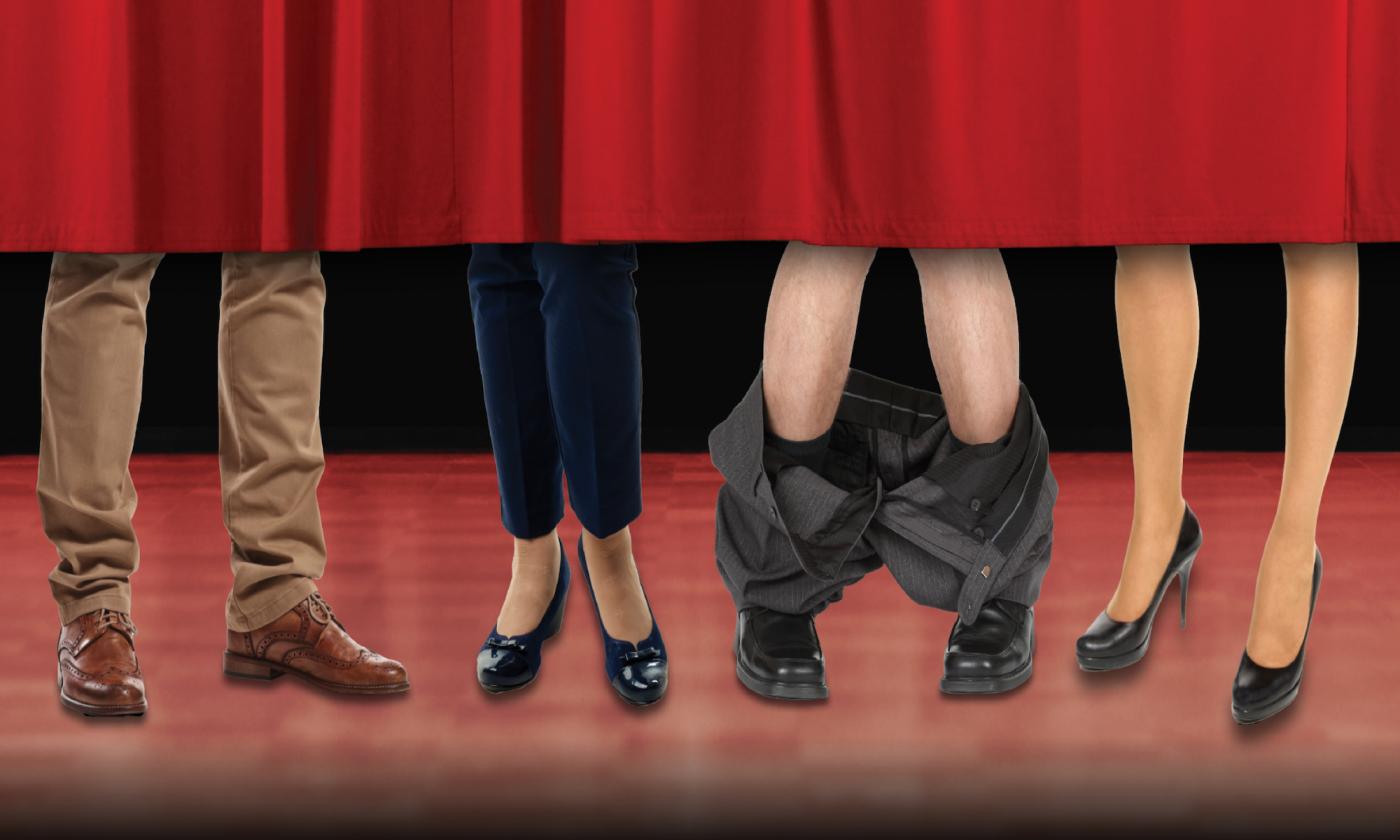 Two female sets of legs and two male sets of legs under a red curtain - one male with pants down