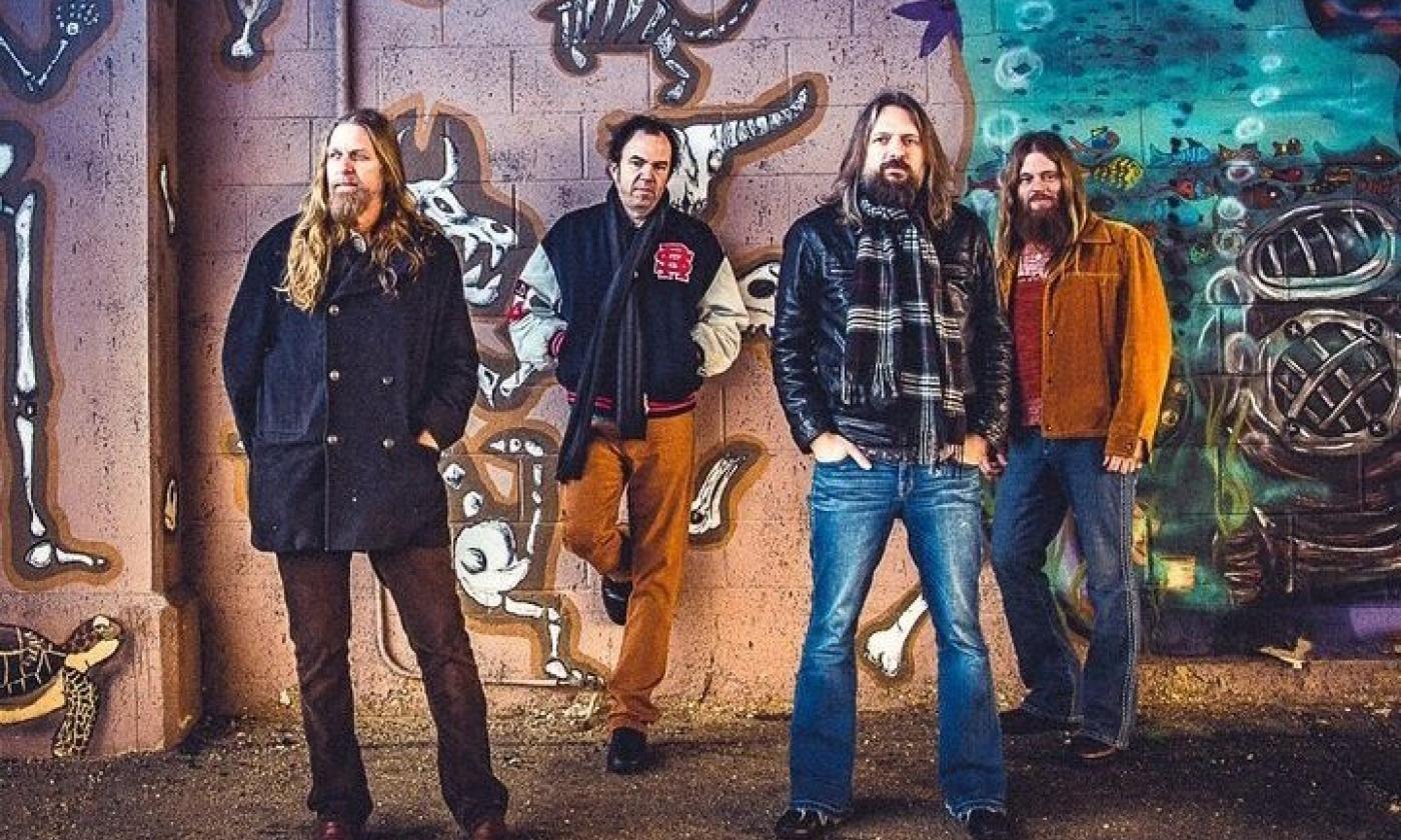 Bandmates from The Steepwater band pose in front of a colorful cement wall.