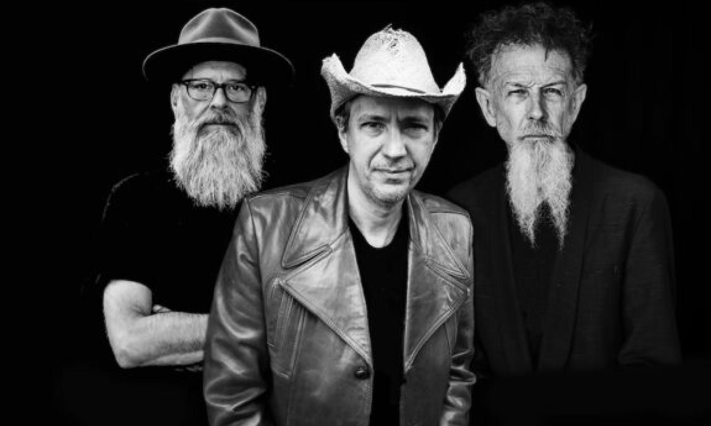 Bandmates from Swamp Cabbage pose in hats in front of a black backdrop.