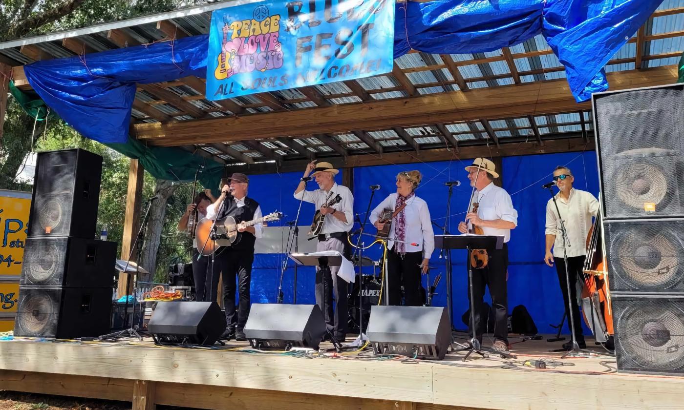 A group of musicians, on an outdoor stage between numbers