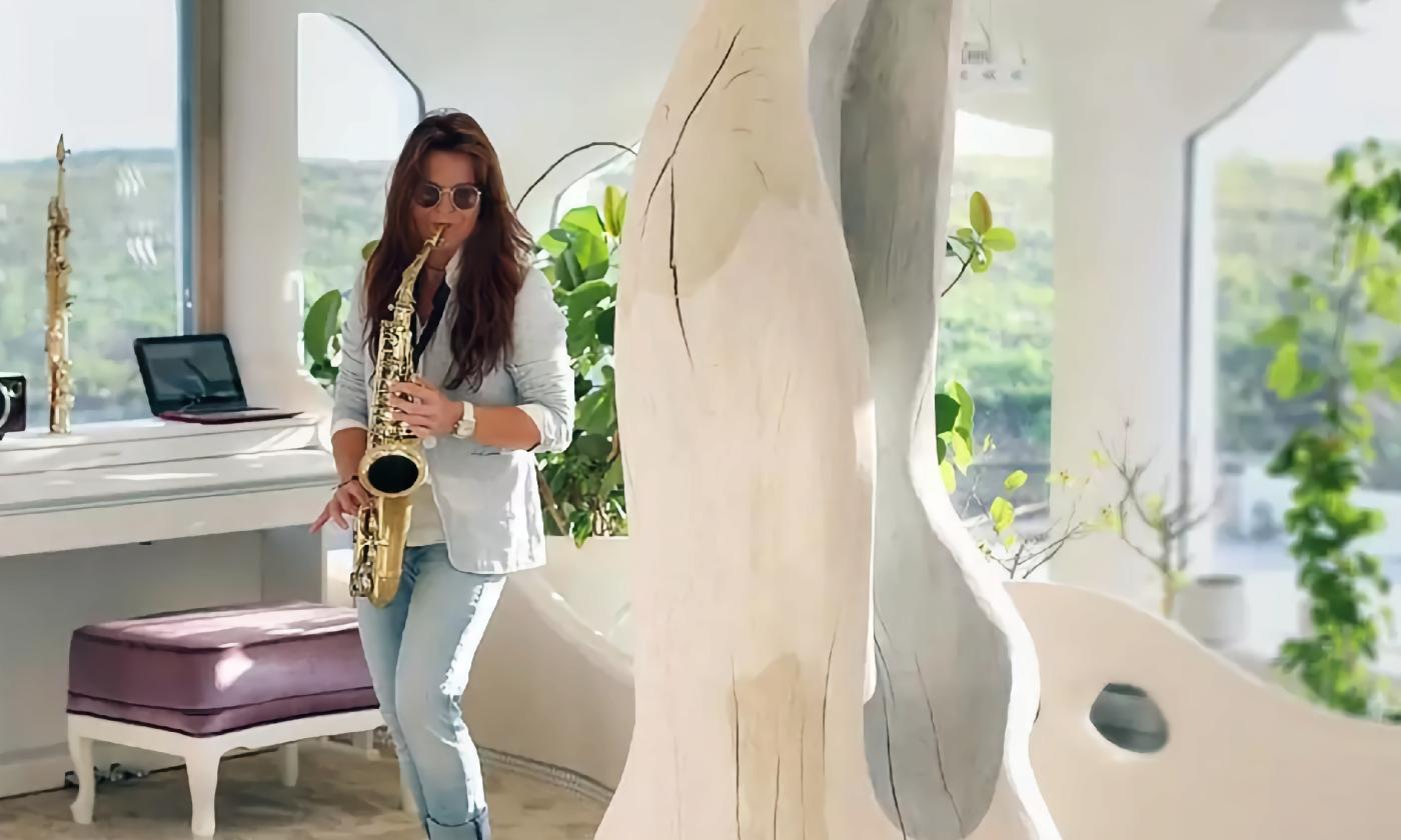 Karina, in washed out jeans and a pale blue blazer, plays alto sax on a lovely deck