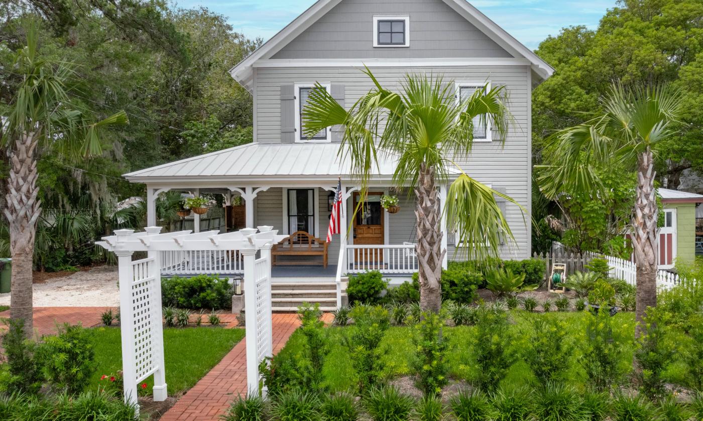 A charming older grey-painted home with a wrap-around porch 