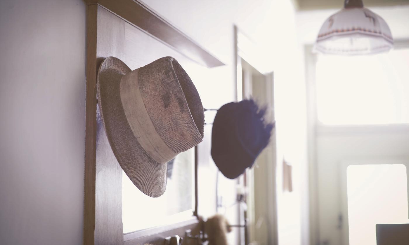 Two old-fashioned hats, hang on hooks on a mirror in a hallway