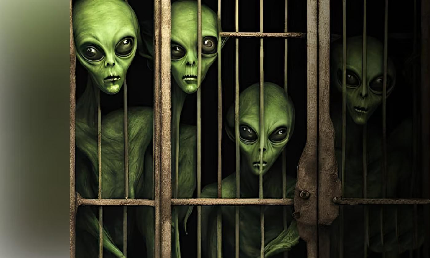 Four green aliens look through the bars of a dark jail cell