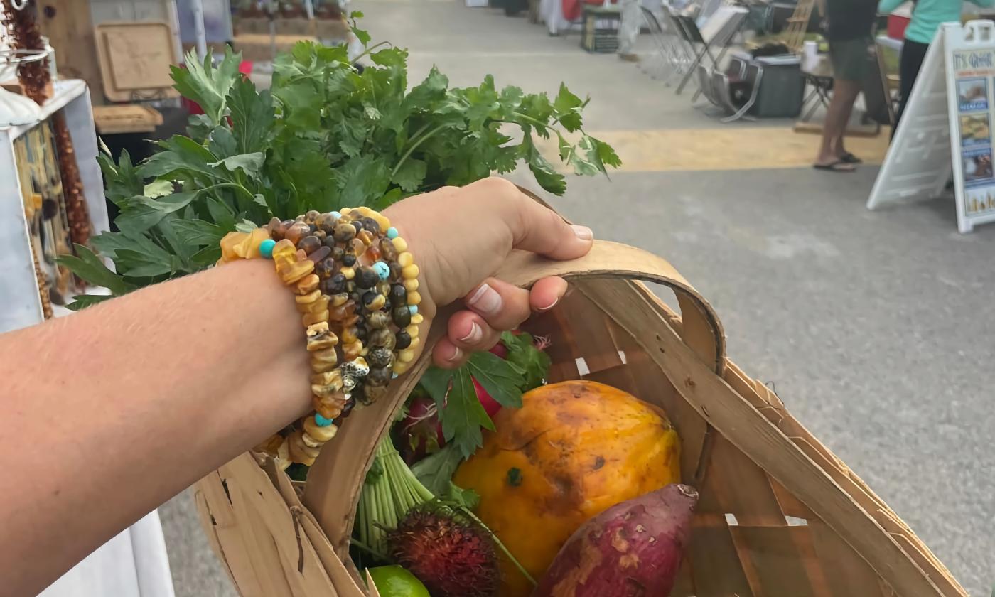 A wooded trug carried by a woman with filled with fresh herbs and fruits