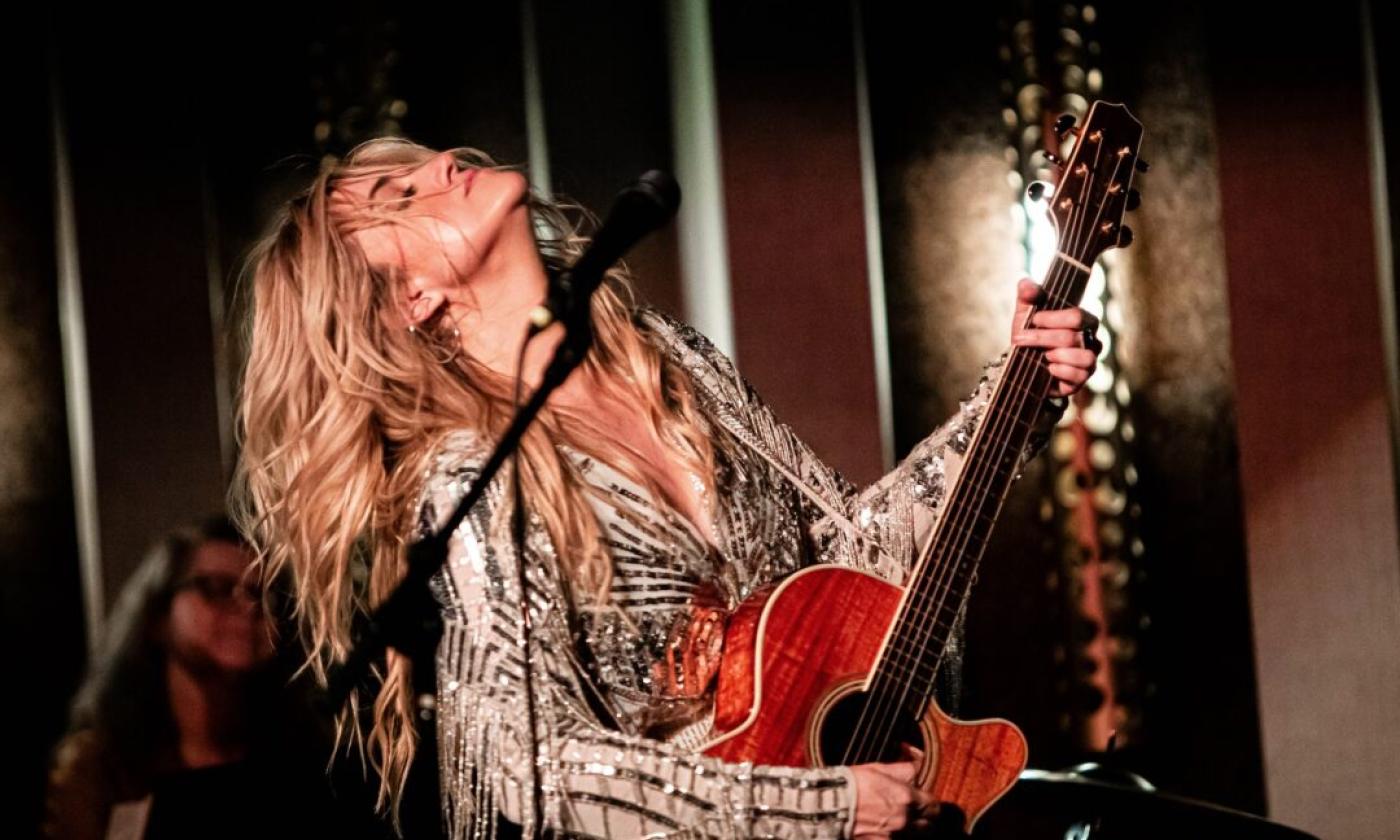 Morgan Myles performs on stage with her guitar.