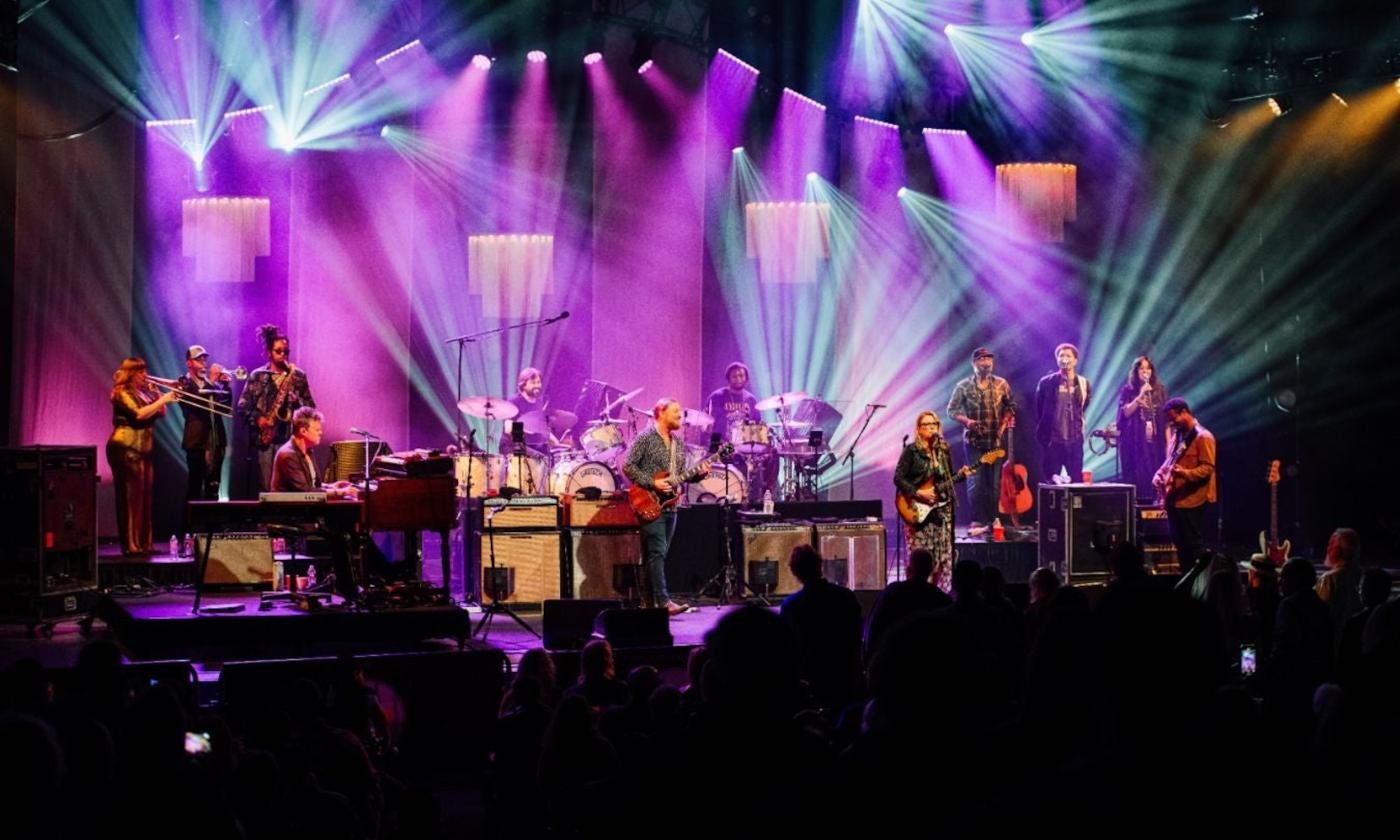 Bandmates from Tedeschi Trucks perform in front of a large audience.