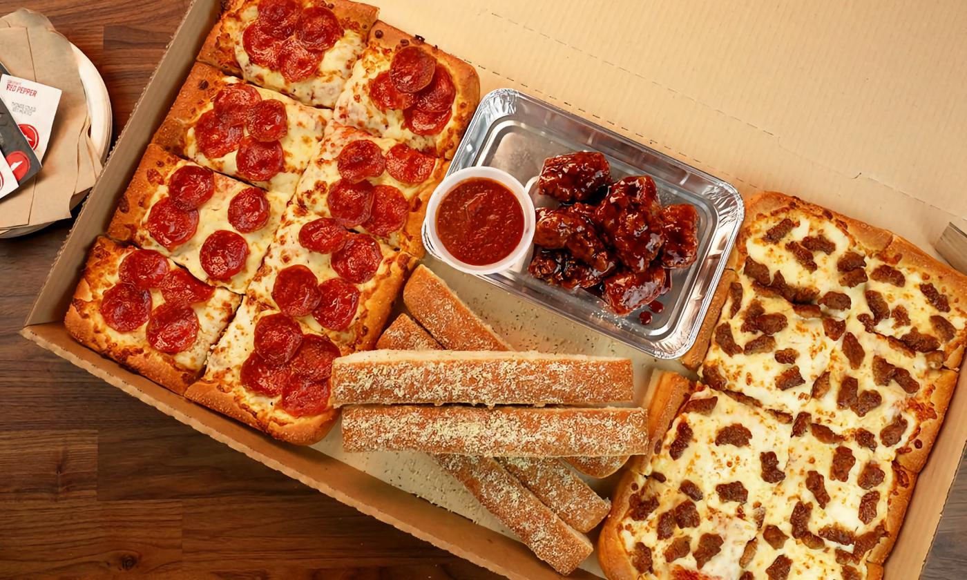 A dinner box including pizza, breadsticks, and wings