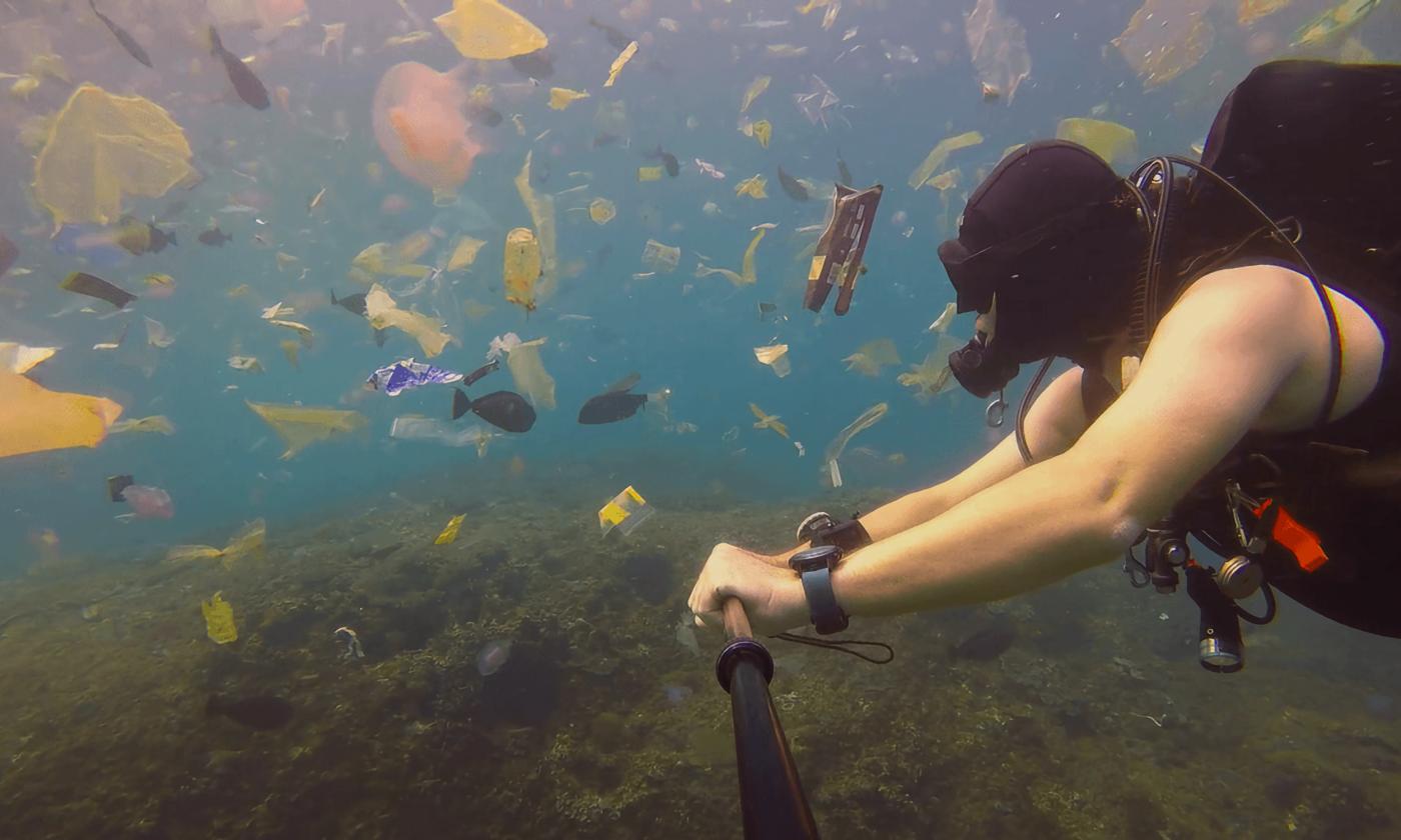 A diver swimming in plastic and other trash in the ocean