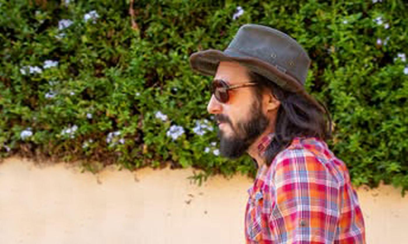 Songwriter-singer Paul Orehovec in black fedora standing in front of ivy covered wall