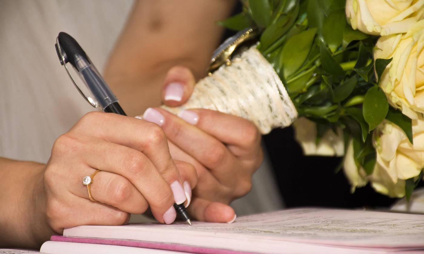 A bride signing the marriage record. (Photo courtesy of Pixabay.)