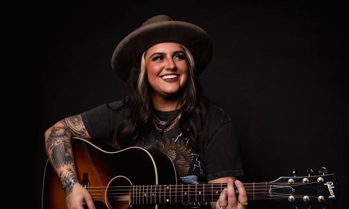 Singer songwriter Austin Taylor Dye with her guitar and a big grin. 