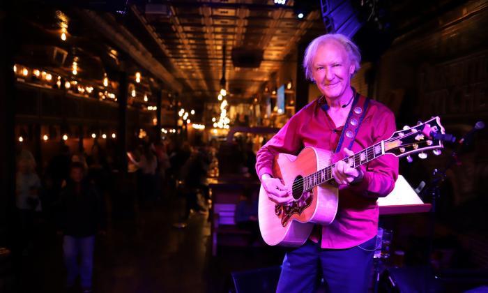 Musician Douglas Arrington standing with his guitar in a bar