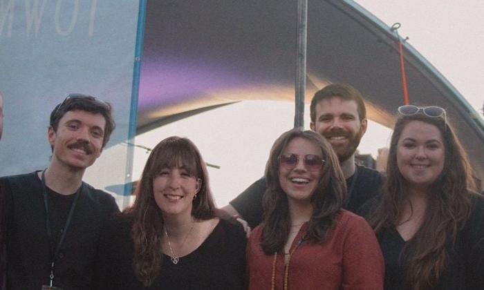 Cat ridgeway and the Tourist band, smiling, in front of performance hall.