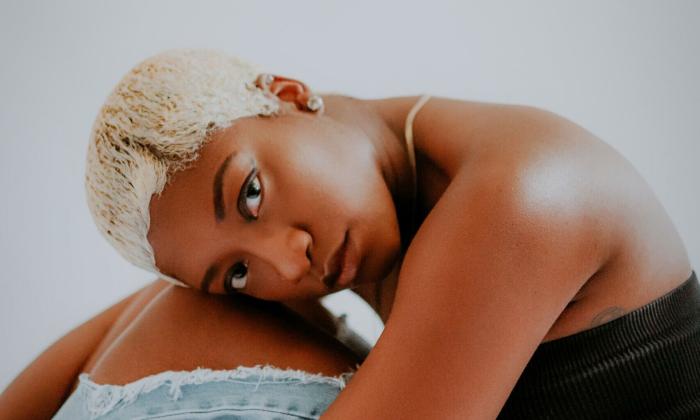 Rhythm and blues musician Ebonique sitting, with head on knees. 