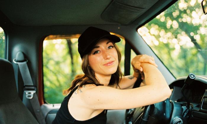 Lauren Hungate at the wheel of her truck, parked by a grove of trees