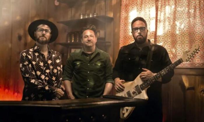 Bandmates from The Cold Stares pose in front of a bar. 