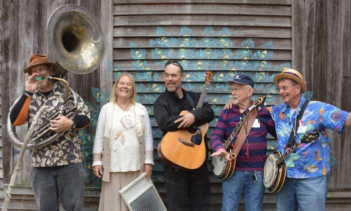 The Ancient City Slickers standing against a mural on a weathered-board building, Gail Carson, photographer