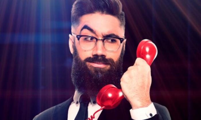 Peter Antoniou holds a phone in his hand and poses in a suit.