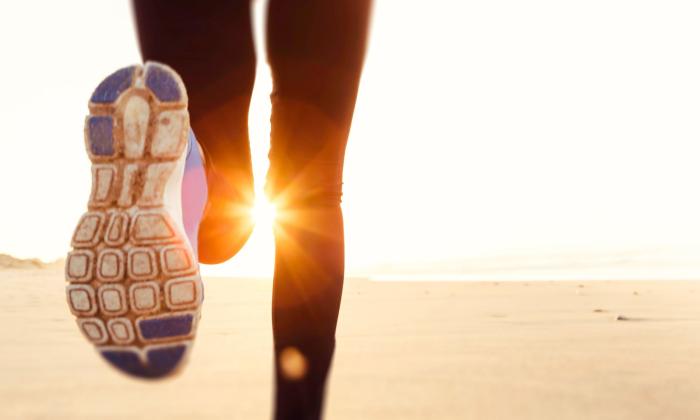 Runner on the beach with the sun on the horizon