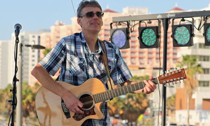 Greg Culp clutches his guitar while performing on stage. 