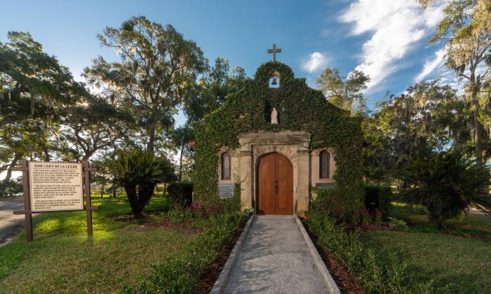 Vine-covered exterior of the National Shrine of Our Lady of La Leche, a Spanish mission style building surrounded in Florida greenery.