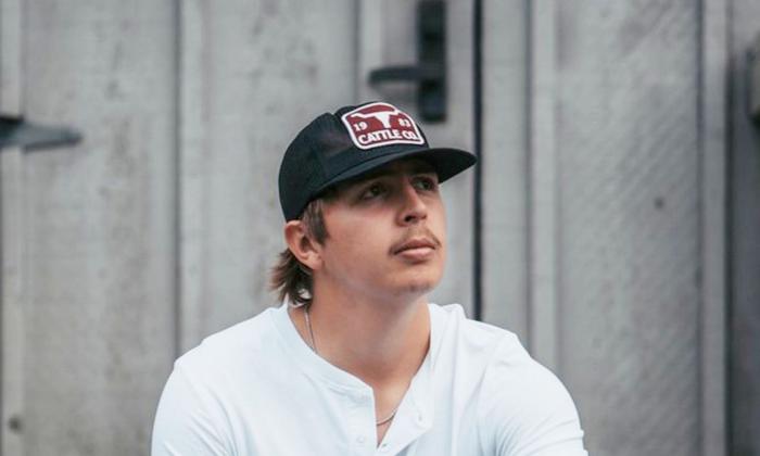 Singer songwriter Hunter Hays in ball cap and white shirt in front of barn