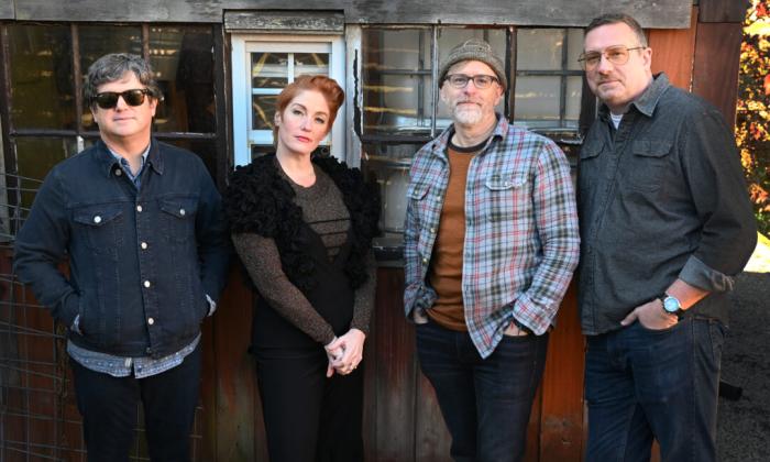 Bandmates from Six Pence None The Richer pose in front of a wooden window. 
