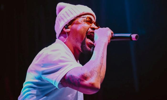 Juvenile wears a knitted hat and t-shirt while performing on stage. 