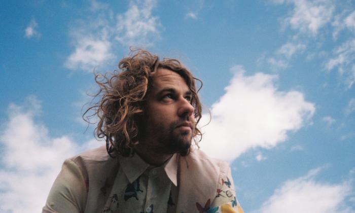 Musician Kevin Morby under a blue sky with soft clouds