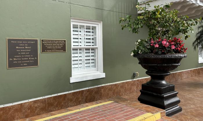 Two bronze plaques mounted on an outside wall above a set of brick steps.