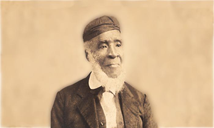 Sepia photograph of an old Black man (Luis Fatio Pacheco) in a hat and suit. His white beard circles his chin from ear to ear.