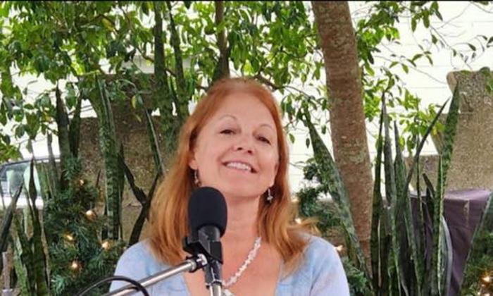 Musician Jo Crowder, singing in front of a microphone, outside