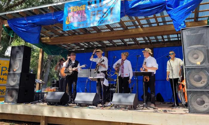 A group of musicians, on an outdoor stage between numbers